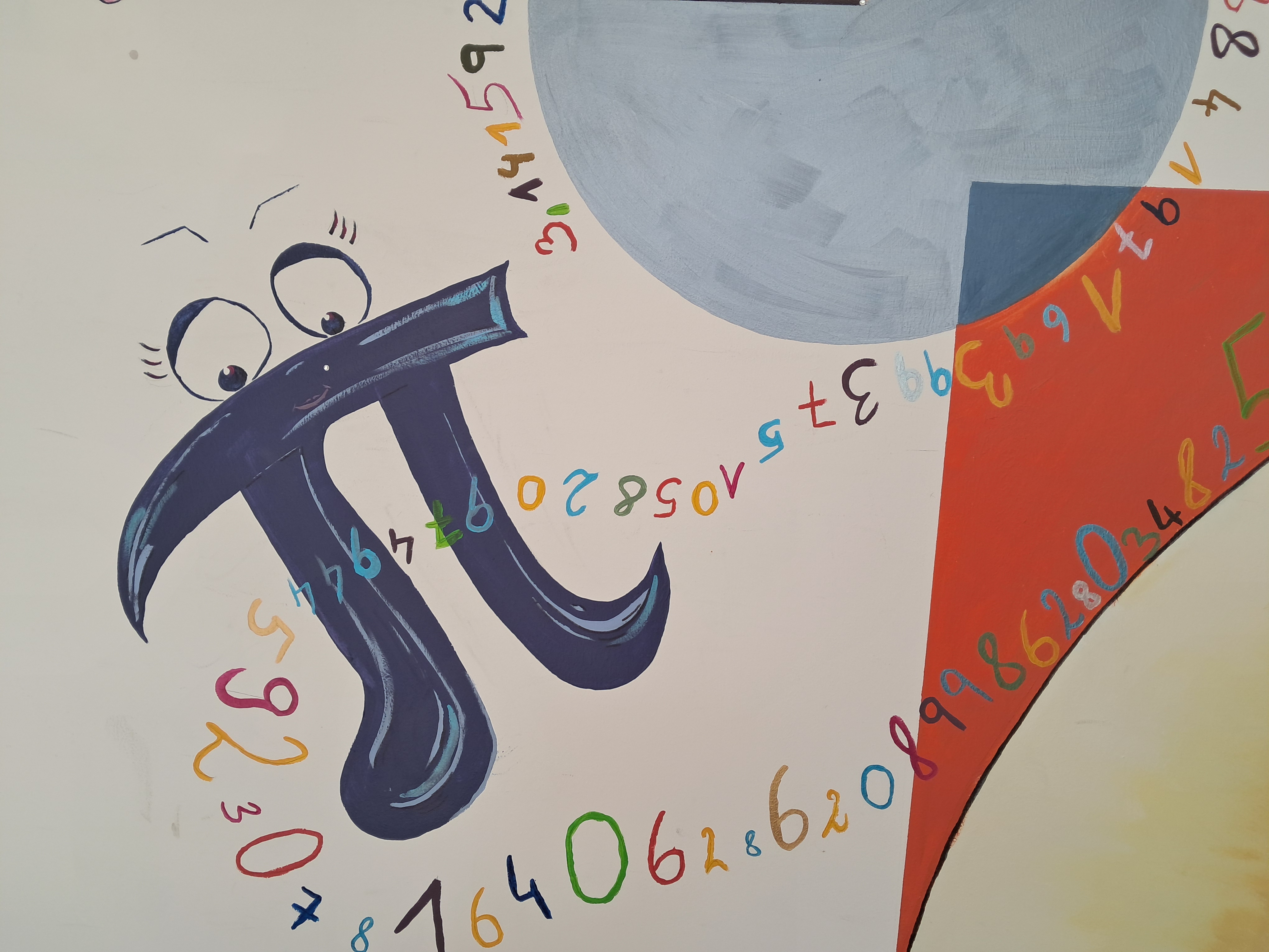 Zusehen ist eine Wand auf der verschiedenen Teile geometrischer Figuren gezeigt werden. Im Fokus ist eine Figur die das Symbol Pi zeigt. Jedoch ist diese als Mäxchen mit Augen, Mund und Stubsnase gemalt. Um die Figur schlängeln sich duzende Nachkommastellen der Zahl PI.